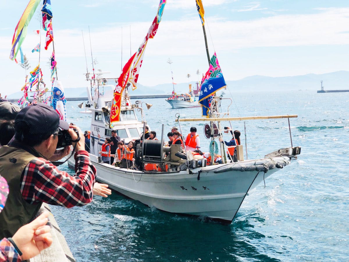 『漁船団パレード』では、華やかな大漁旗をたなびかせた漁船から紅白の餅まきも行われる