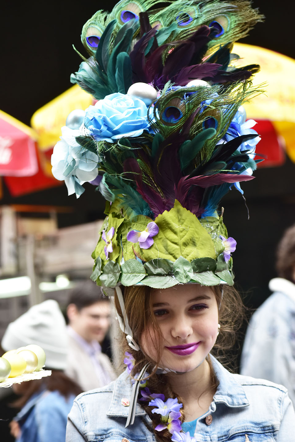 少女がかぶるには少し背が高い？孔雀の羽が豪華さを演出しています。