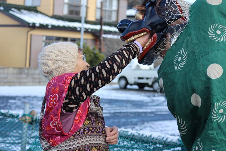 2015年の春祈祷の様子。獅子の口にお金を入れている貴重なシーンだと、撮影者である渡辺さんは語ります。　2015年に仮設住宅で行われた春祈祷の様子。お囃子は笛と太鼓で構成されています。　写真提供：女川港大漁獅子舞まむし