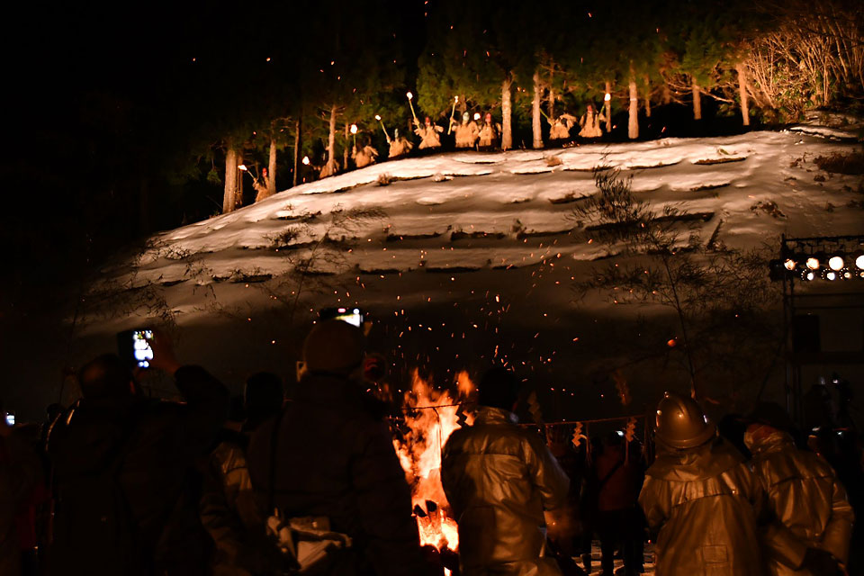 松明を持って雪の上に並んでいるなまはげ