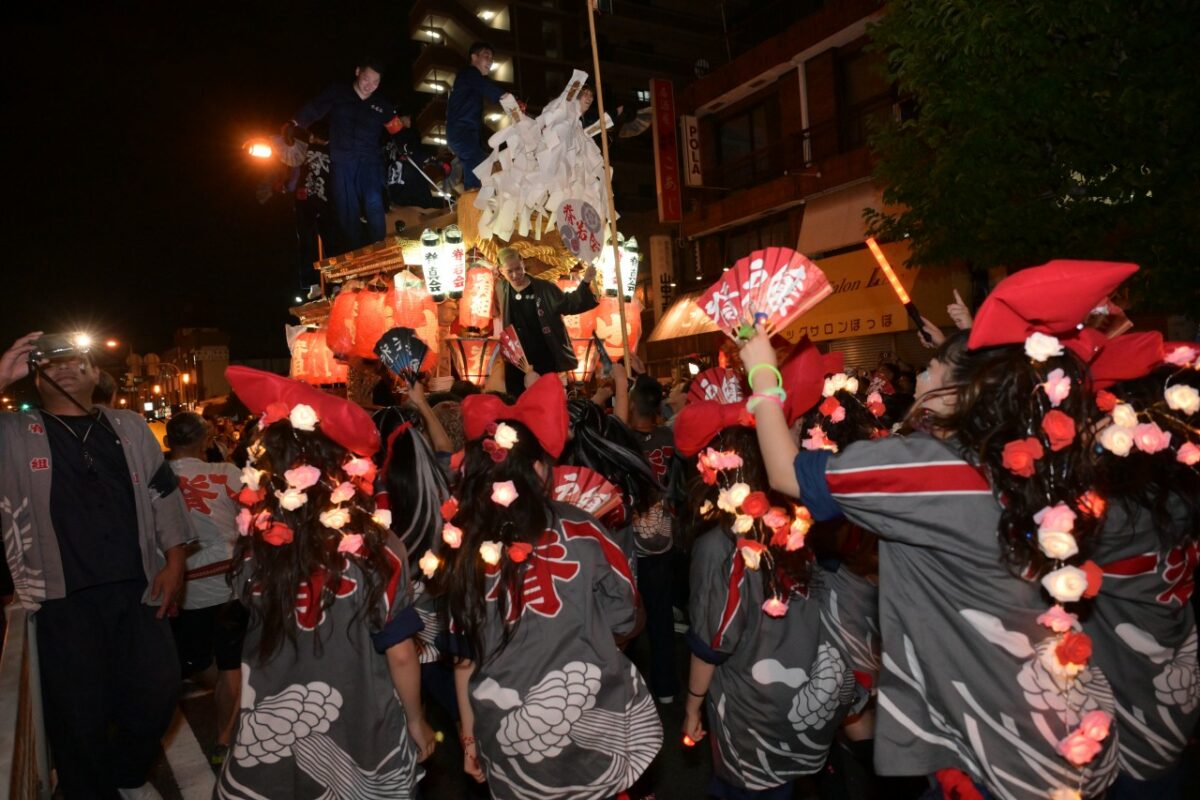 背戸口町のだんじりと派手な花の電飾をつけた若い女性たち（脊戸嬢）